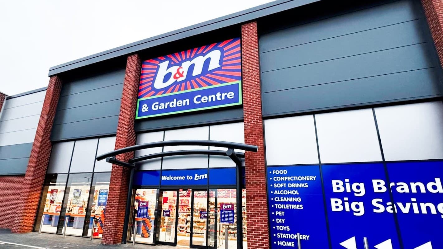 B&M store entrance featuring a garden centre, with bright signage and various product categories displayed.
