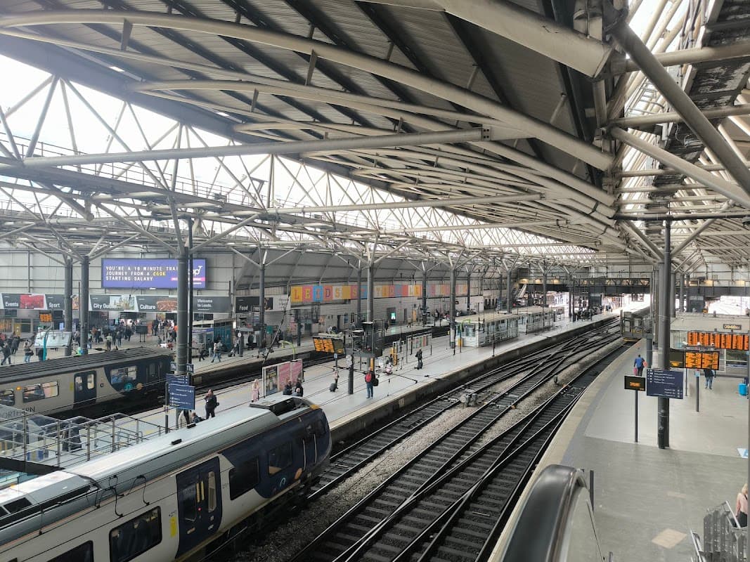 Pay & Display car park at Leeds Station, with trains and passengers under a large, open roof structure.