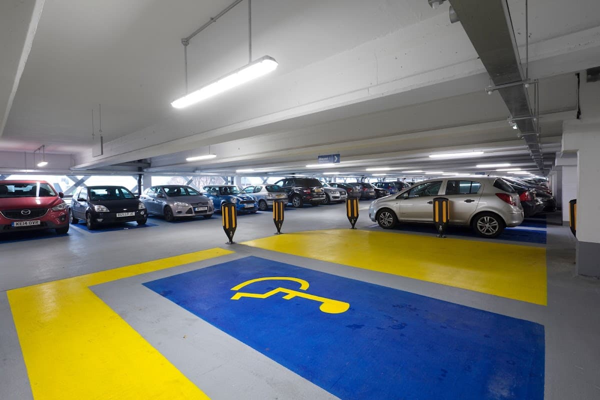 Pay & Display parking area with marked disabled space, cars parked, and bright overhead lighting in Leeds.