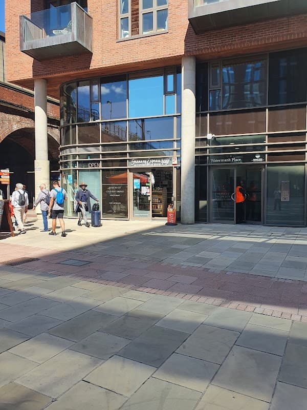 Granary Express Off License storefront with large windows, people walking by, and modern brick architecture in Leeds.