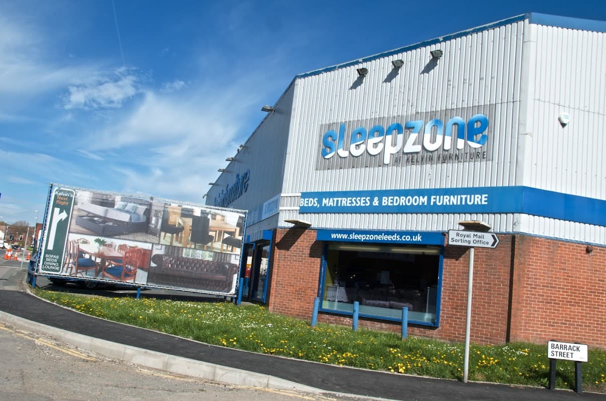 Exterior of Kelvin Furniture shop with a large advertisement showcasing furniture, located on a sunny street in Leeds.