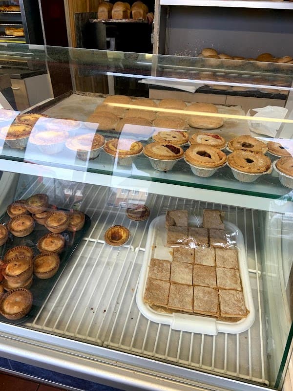 Display case filled with various baked goods, including pastries, pies, and squares, in a bakery setting.