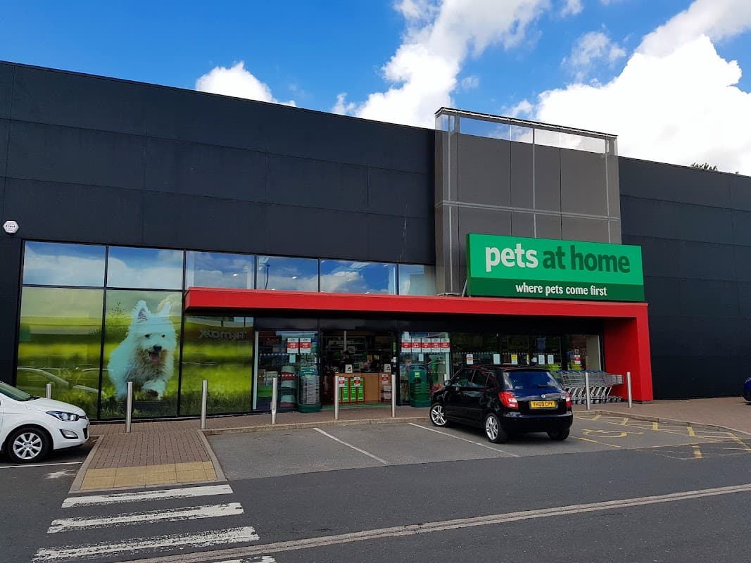 Storefront of Pets at Home in Leeds, featuring a large sign, green accents, and a dog image on the window.