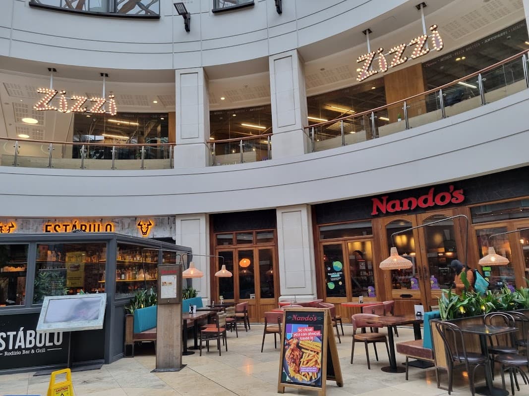 Shopping centre interior featuring Zizzi and Nando's restaurants, with seating and decorative lighting.