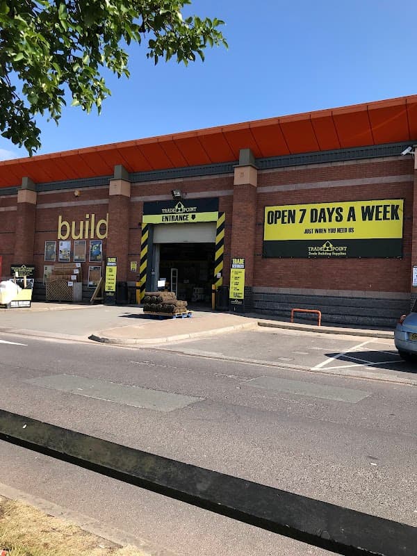 TradePoint Leeds storefront with yellow signage, entrance, and a nearby parked car on a sunny day.