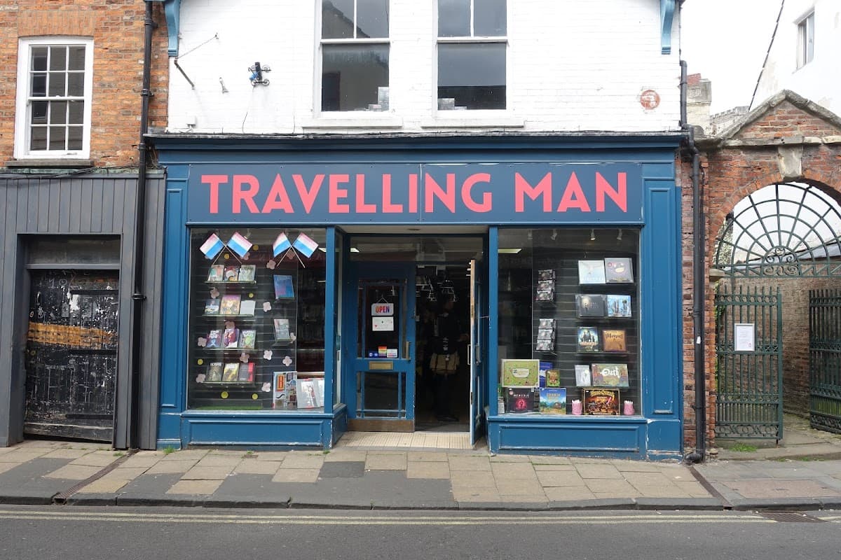 Bright blue storefront with "TRAVELLING MAN" in bold red letters, displaying books and colorful bunting.