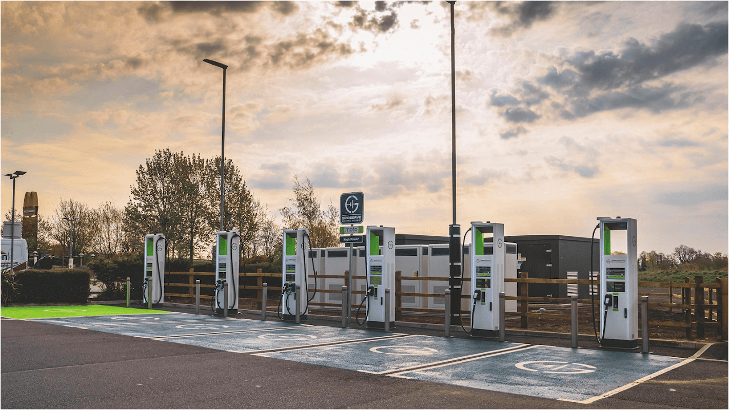 GRIDSERVE Charging Station with multiple EV chargers, surrounded by trees and a cloudy sky in Leeming Bar, Yorkshire.
