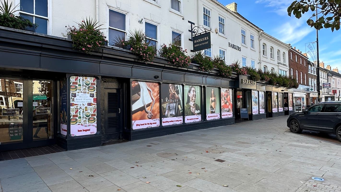 Storefront with large posters, flower boxes, and a sign for "Bakers" in Leeming Bar, Yorkshire.