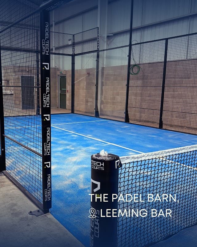 Indoor padel court with blue flooring, surrounded by black mesh fencing, featuring branding for ProTech Sports.