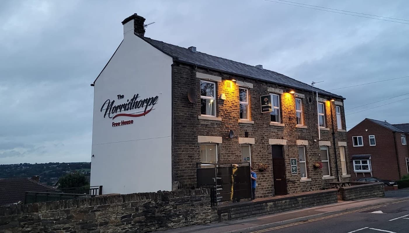 The Norristhorpe bar features a stone exterior, illuminated signage, and a cozy street view in Liversedge, Yorkshire.
