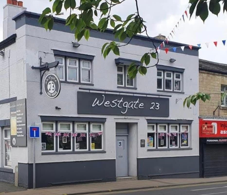 Westgate 23 bar in Liversedge, featuring a gray exterior, large windows, and festive bunting.
