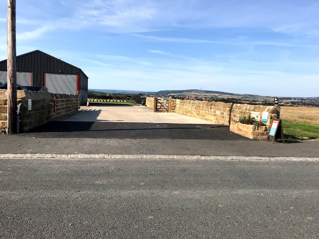 Stone wall entrance to Poverty Cottage CL, with a gravel drive and scenic countryside views in Low Hawsker, Yorkshire.