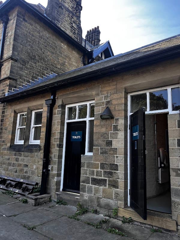 Free parking area with a stone building featuring two restroom doors labeled "TOILET'S."