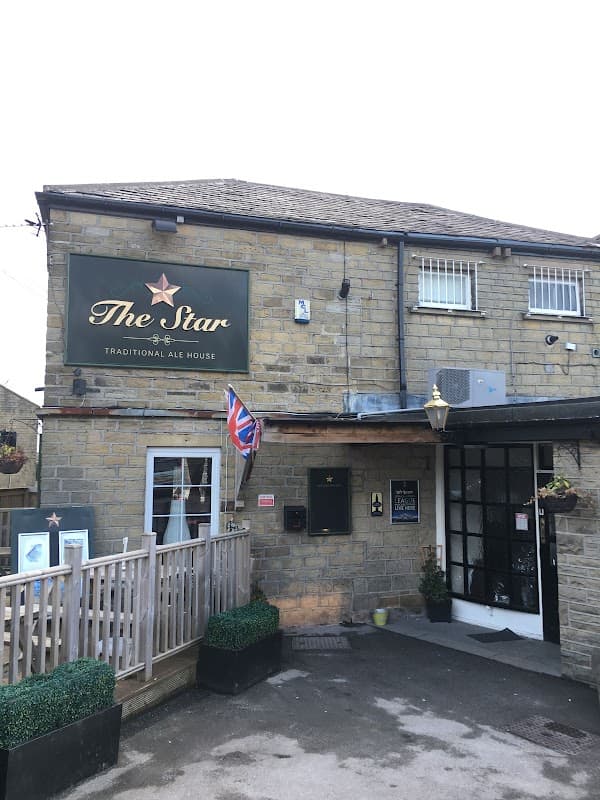 Traditional stone pub with a sign reading "The Star," British flag, and planters at the entrance in Lower Cumberworth.