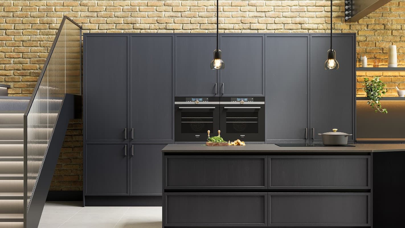 Modern kitchen showroom featuring dark cabinetry, built-in ovens, and a stylish island with minimalist decor.