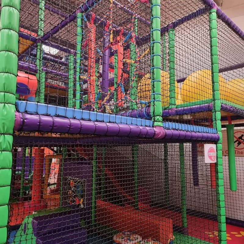 Colorful indoor play structure with nets, slides, and climbing areas for children in a vibrant setting.