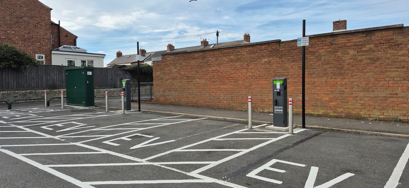 Electric vehicle charging stations in a car park with a brick wall backdrop in Marske, Yorkshire.