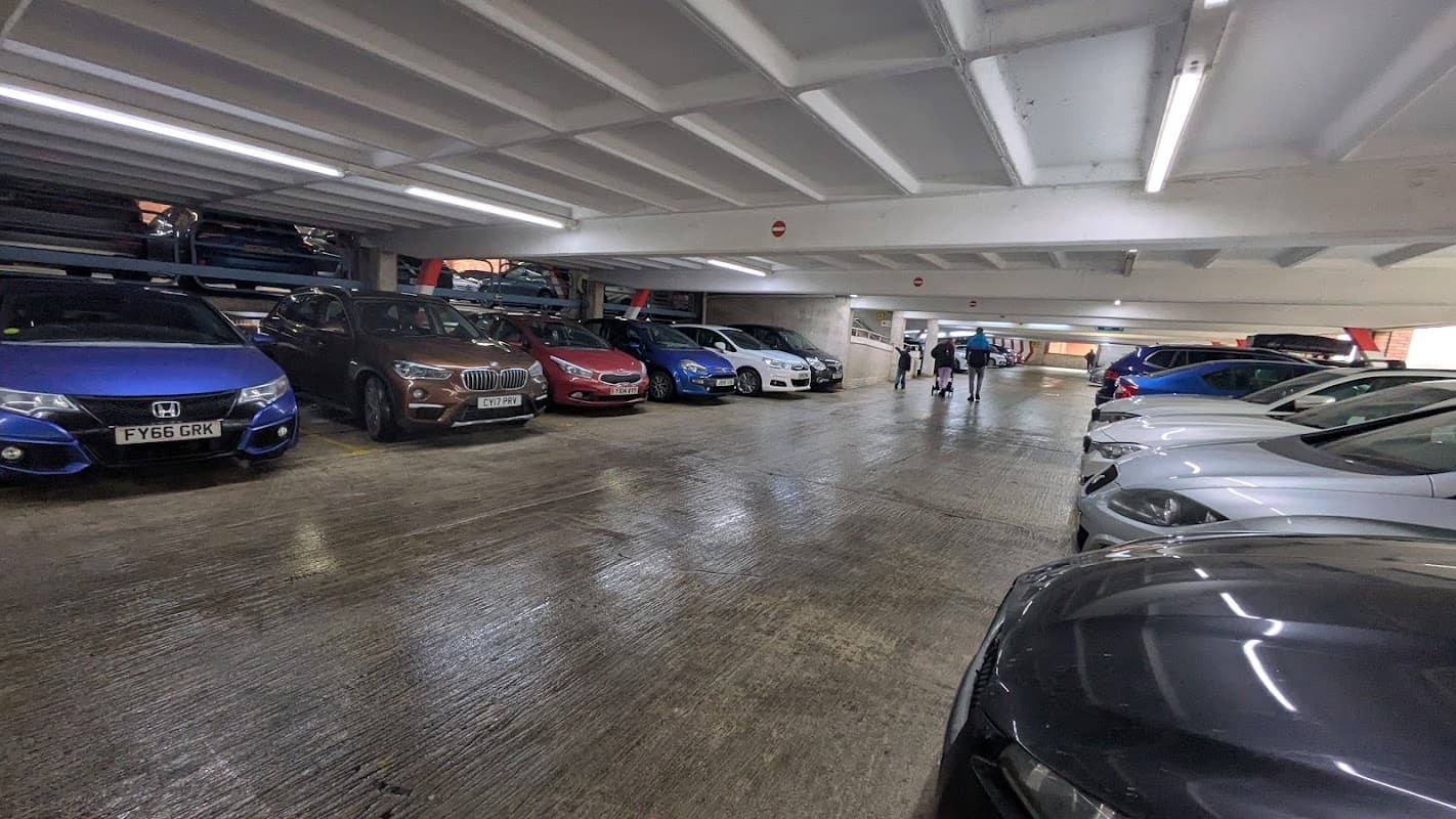 Interior view of Captain Cook Multi Storey Car Park with parked cars and people walking in the background.