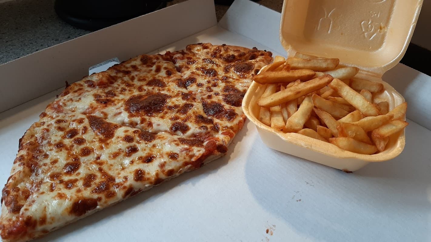 A large slice of cheesy pizza next to a container of golden fries on a pizza box.