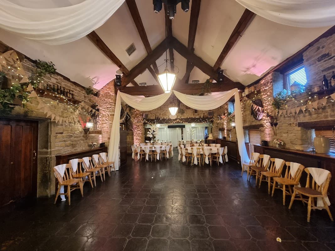Elegant event space with wooden beams, draped fabric, and decorated tables, creating a warm, inviting atmosphere.