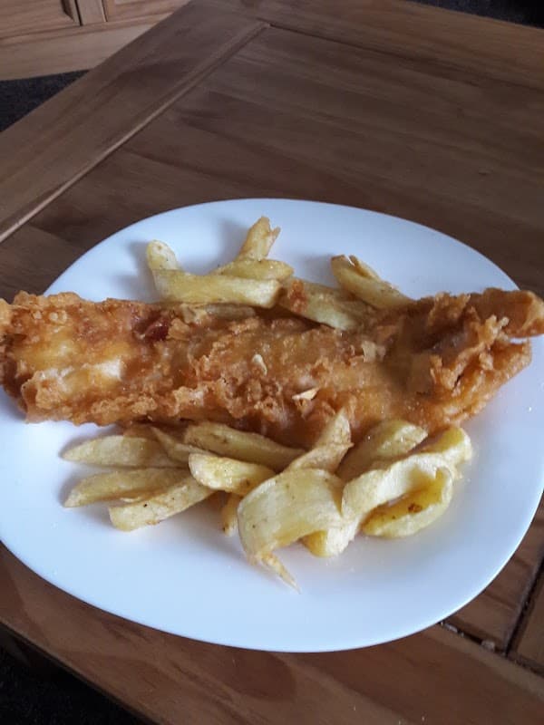 Crispy battered fish fillet served with golden fried chips on a white plate.