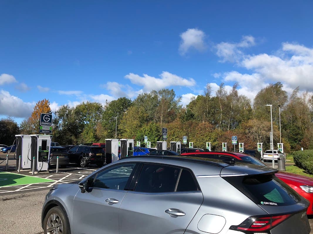 Electric vehicle charging stations at Scotch Corner Services with clear blue skies and autumn trees in the background.
