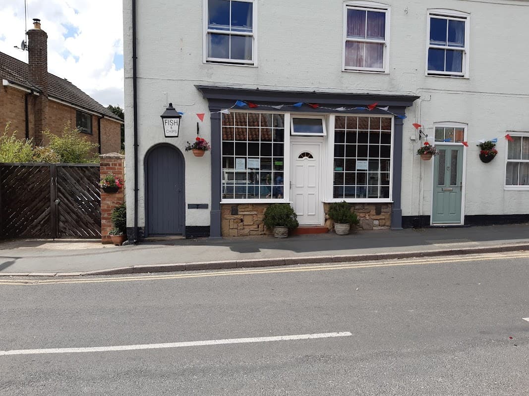 Quaint fish restaurant with large windows, colorful bunting, flower pots, and a blue door in Nafferton, Yorkshire.