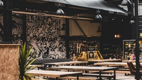 Industrial bar interior with wooden tables, vibrant mural, and modern lighting in Neepsend, Yorkshire.