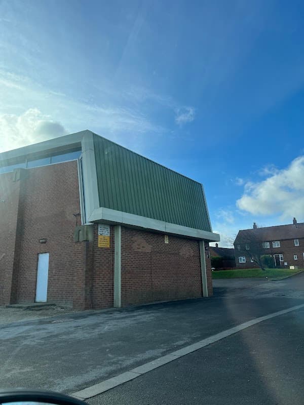 Netherton Village Hall featuring a green roof, brick exterior, and clear blue sky in the background.
