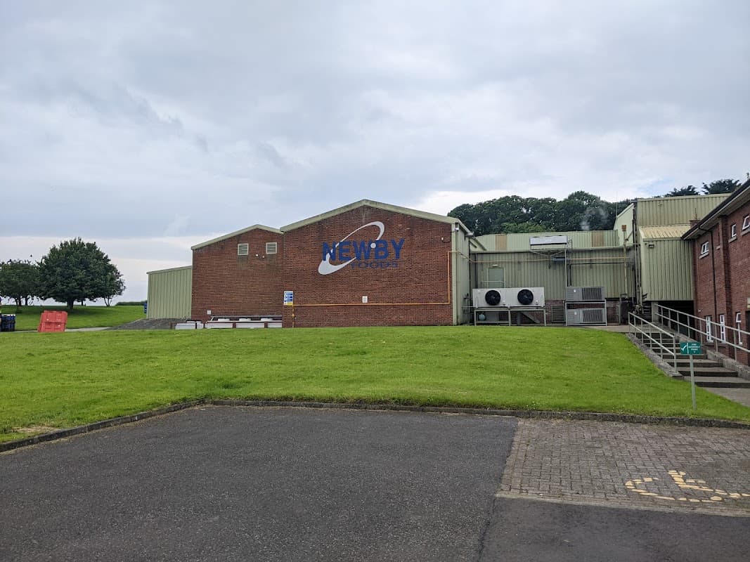 Newby Foods building with a large sign, grassy area, and parking lot in Newby Wiske, Yorkshire.