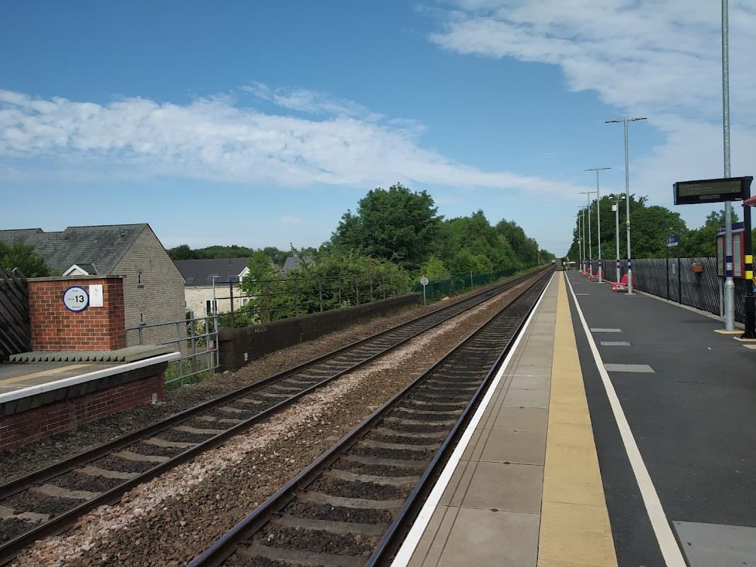 Micklefield Station platform with railway tracks, trees in the background, and clear blue sky.