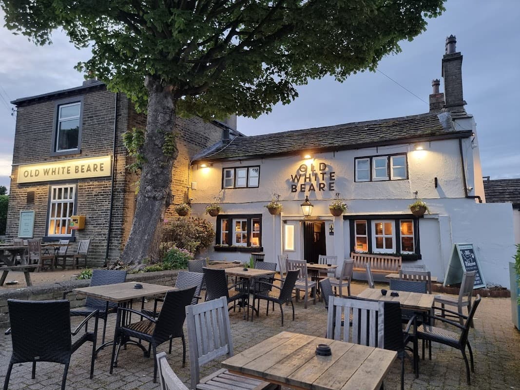 Historic pub with a sign reading "Old White Beare," outdoor seating, and a large tree in a quaint Yorkshire village.