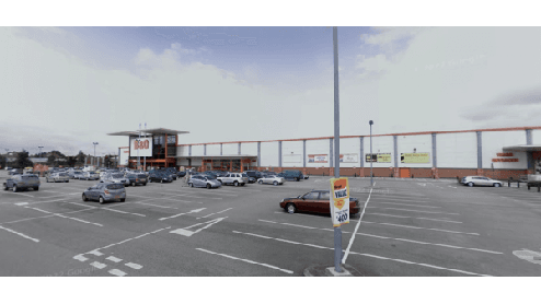 Parking lot with multiple cars and a large retail building in Osbaldwick, Yorkshire, under a cloudy sky.