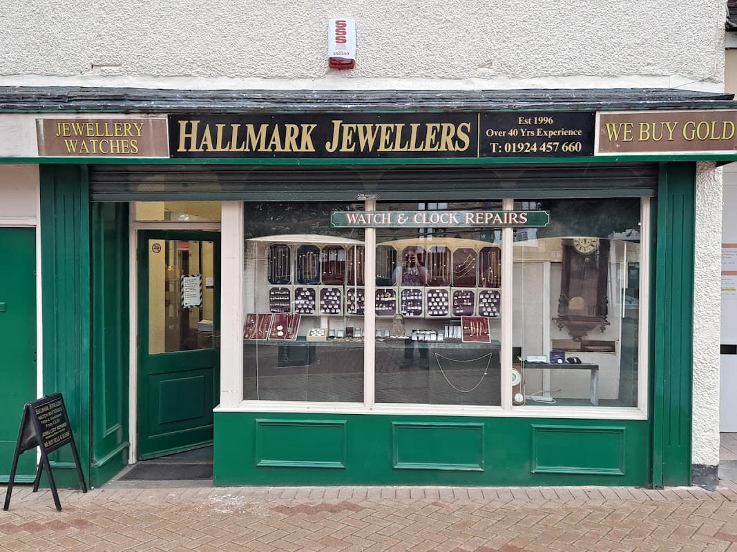 Green storefront of Hallmark Quality Jewellers, featuring displays of watches and jewellery, with a sign for repairs.