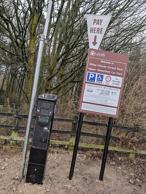 Sign for Upper Shawfield Car Park with payment machine, surrounded by trees in Otley Chevin Forest Park.