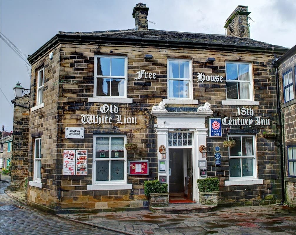 Historic stone building with a sign reading "Old White Lion," featuring a welcoming entrance and decorative plants.
