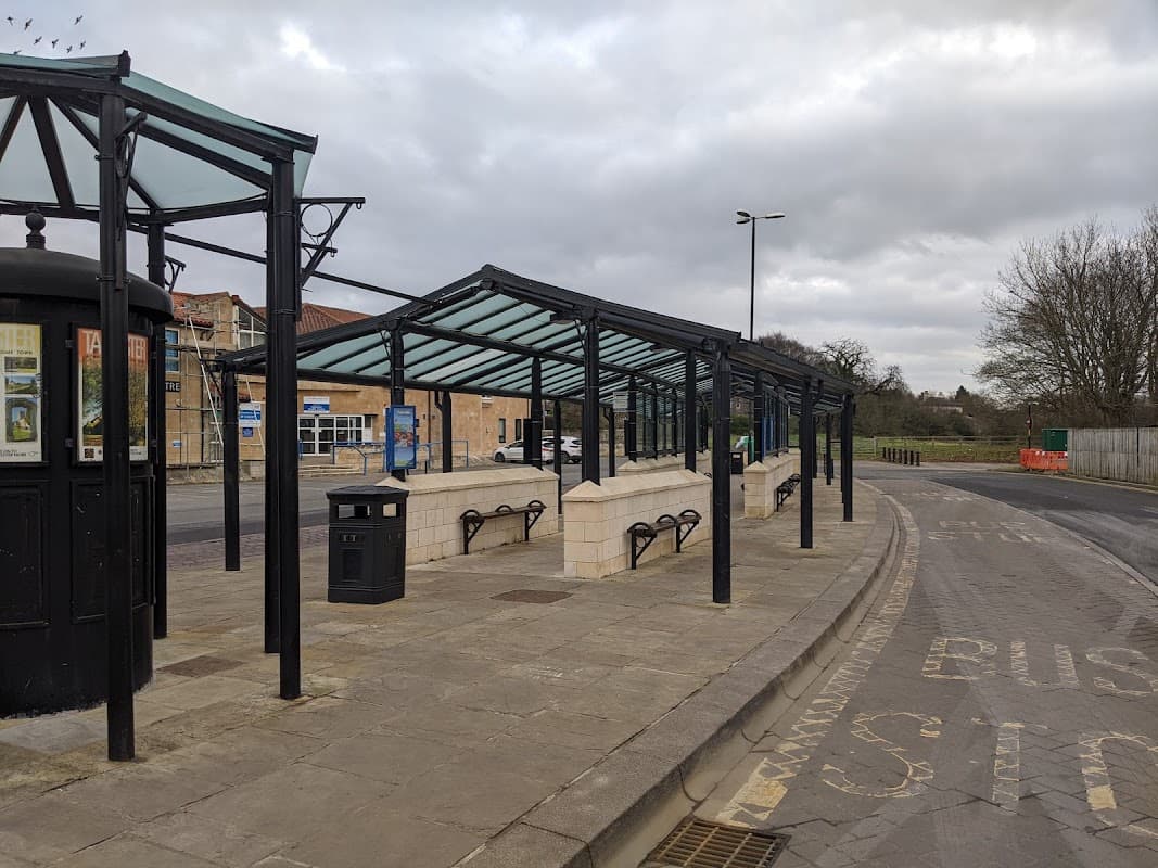Tadcaster bus station features covered waiting areas, benches, and a trash bin along a quiet street.