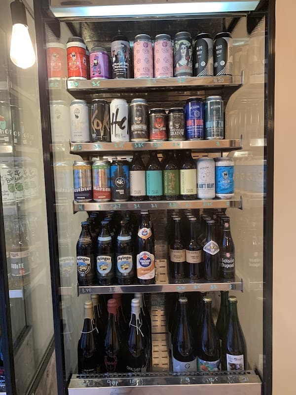 Refrigerated display filled with various craft beer cans and bottles, showcasing a diverse selection of brews.