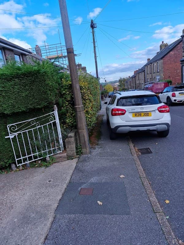 Pay & Display car park in Penistone, featuring parked cars, greenery, and a clear blue sky.
