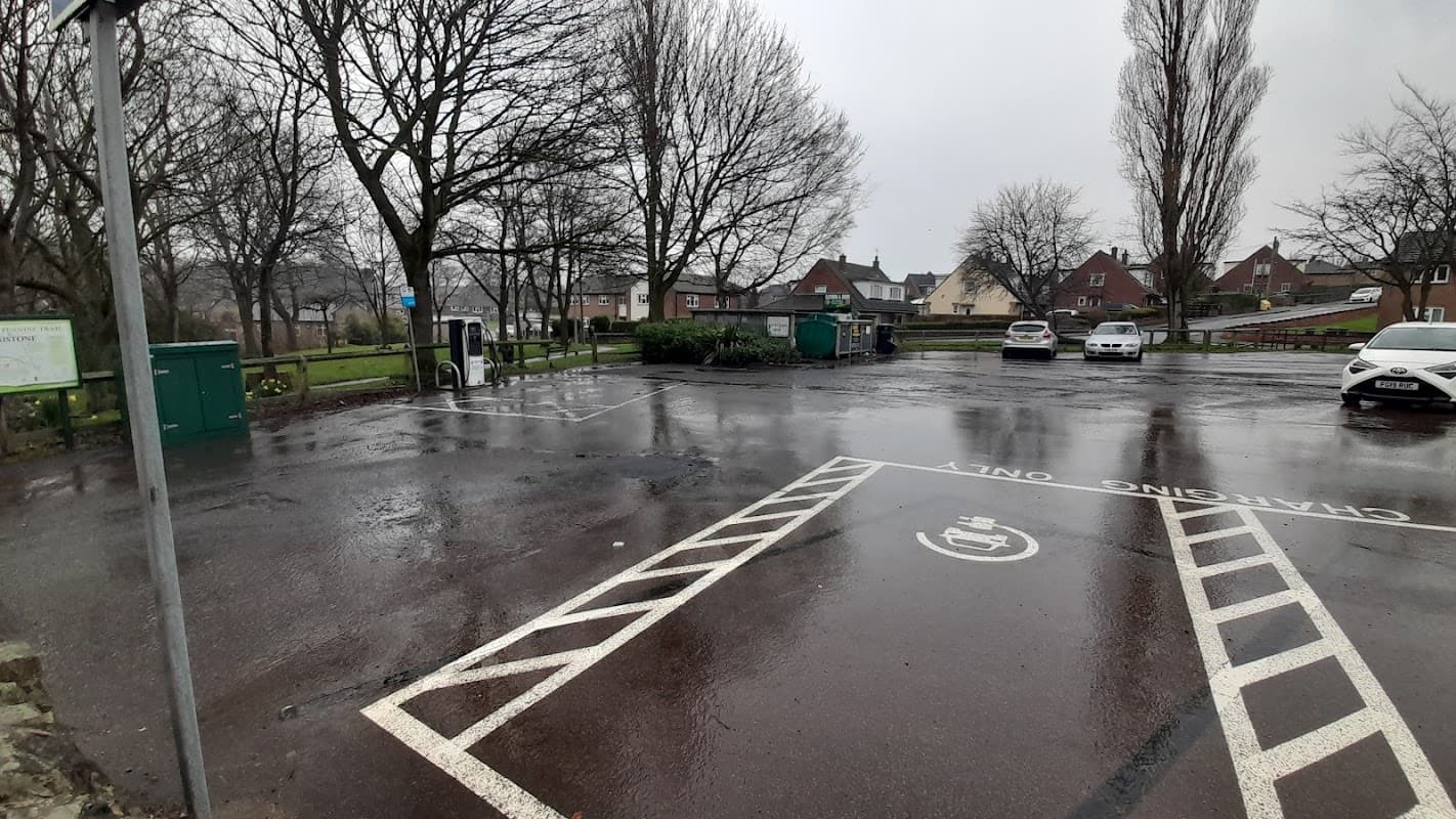 Free parking area in Penistone, Yorkshire, with wet pavement, trees, and parked cars under gray skies.