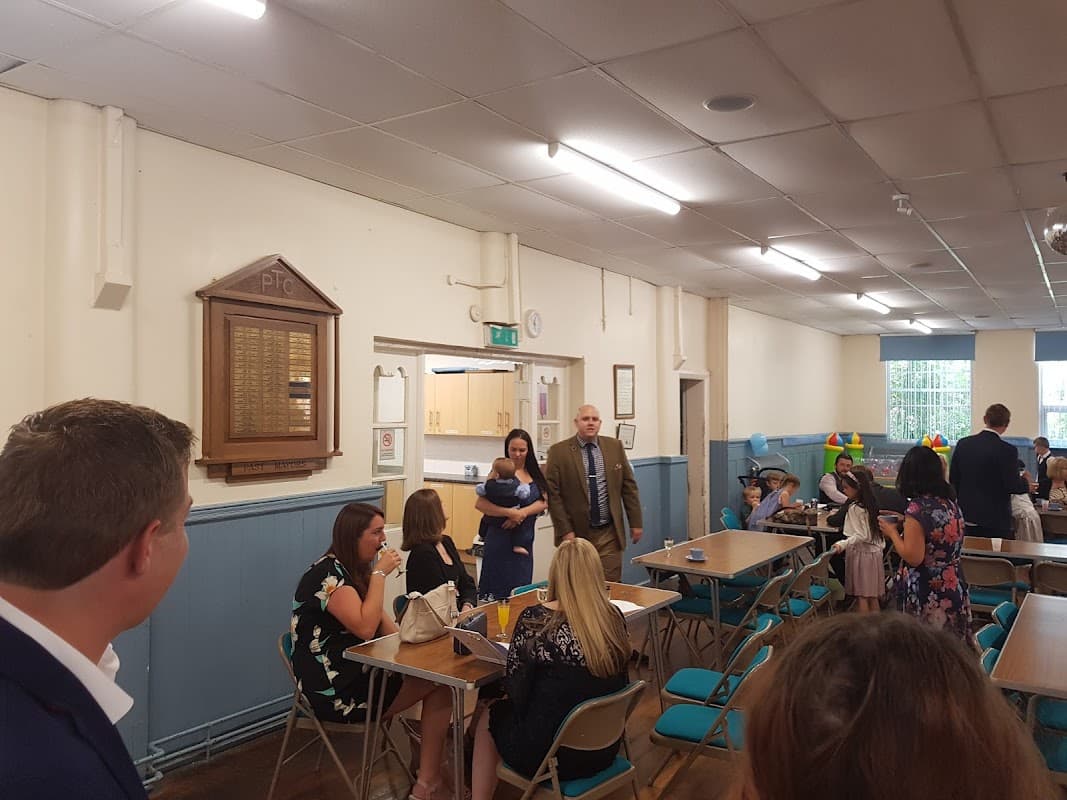 Interior of St Johns Community Centre with tables, chairs, and people mingling during an event.