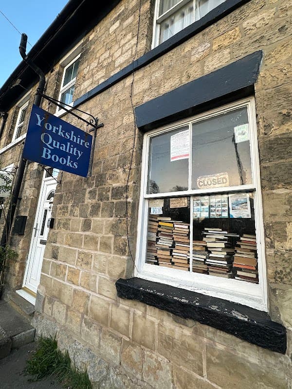 Sign for "Yorkshire Quality Books" above a closed window displaying stacked books in a stone building.