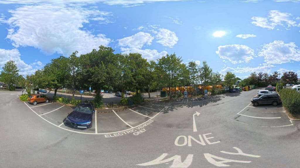 Zest Charging Station in Pickering, featuring electric vehicle parking, trees, and a bright sky with scattered clouds.