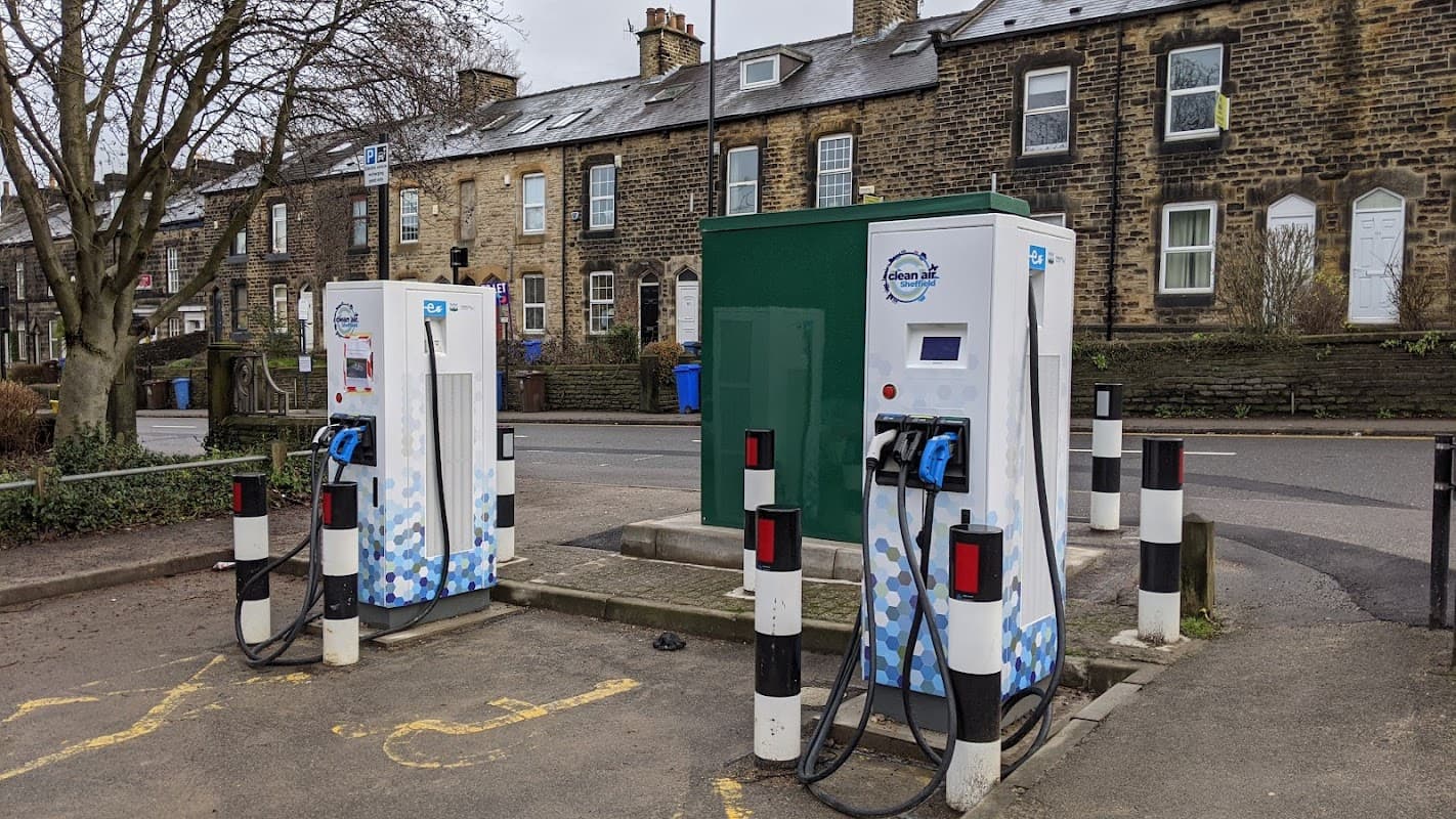 Pay & Display electric vehicle charging stations at Parker's Lane Car Park, surrounded by stone buildings and trees.