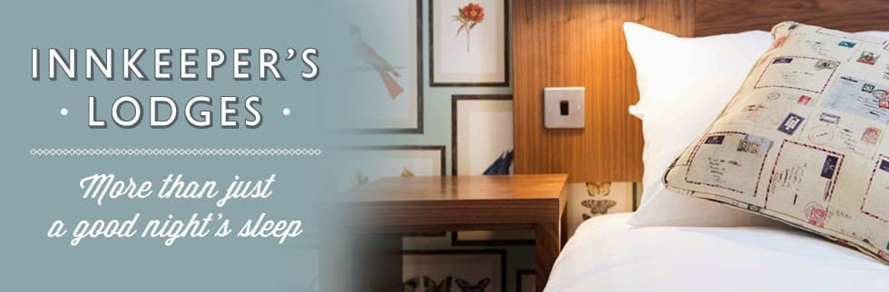 Cozy lodge interior with a decorative pillow, bedside table, and elegant wall art in a warm atmosphere.