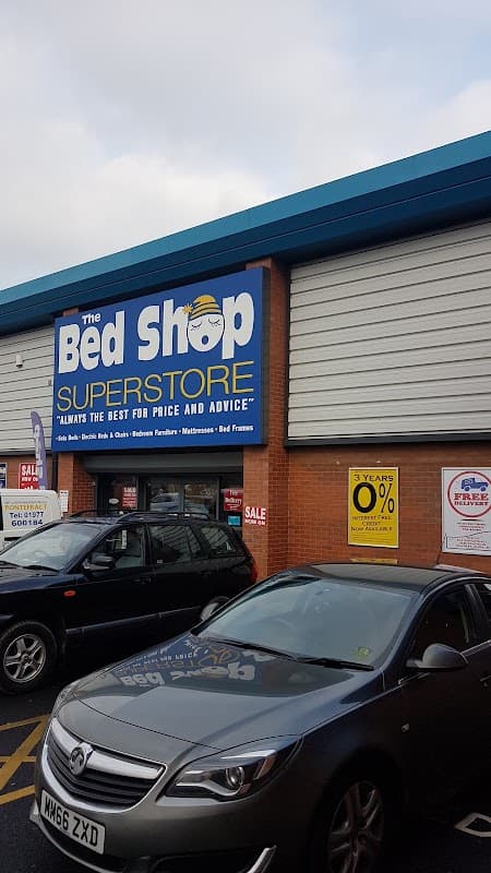 The Bed Shop Superstore storefront with blue signage, parked cars, and promotional sale signs.
