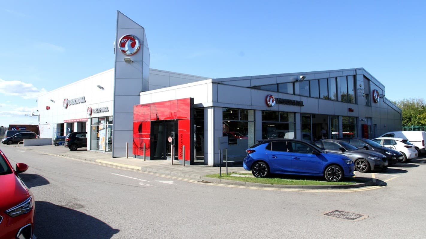 Vauxhall dealership in Redcar, featuring a modern building and several parked cars in front. Clear blue sky above.