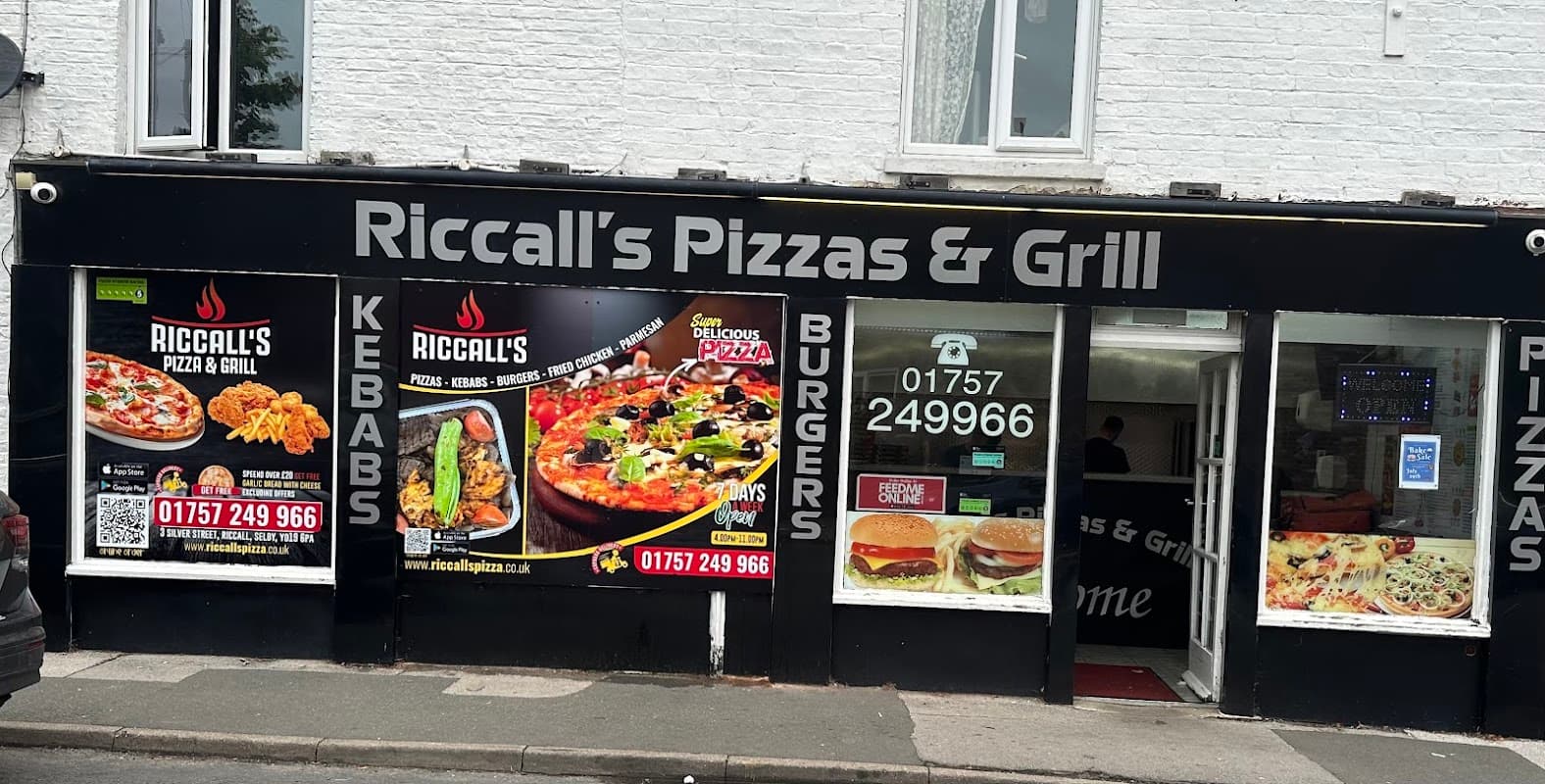 Signage for Riccall's Pizza & Grill featuring pizza, kebabs, and burgers, with contact details and colorful food images.