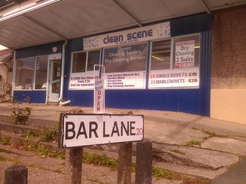 "Clean Scene storefront with signs for duvet cleaning services and a 'Bar Lane' street sign in front."