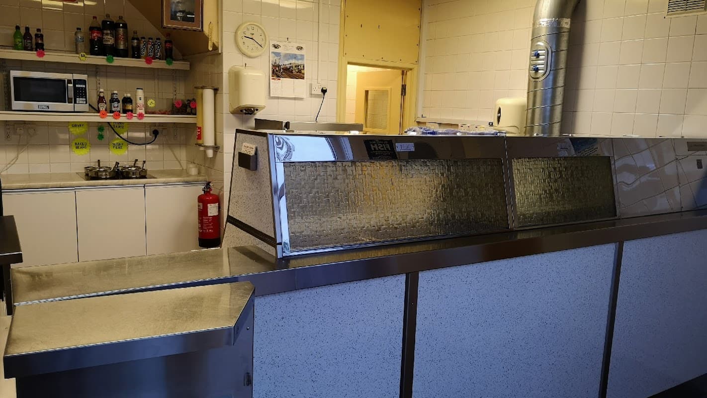 Interior of Riddlesden Fisheries featuring a stainless steel counter, fryer, and kitchen appliances.